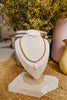 Necklace with a pendant on a beige bust in front of yellow flowers