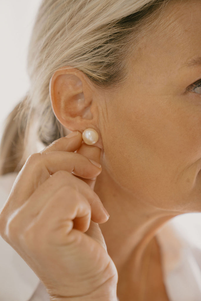 Close-up of a person wearing a pearl earring.