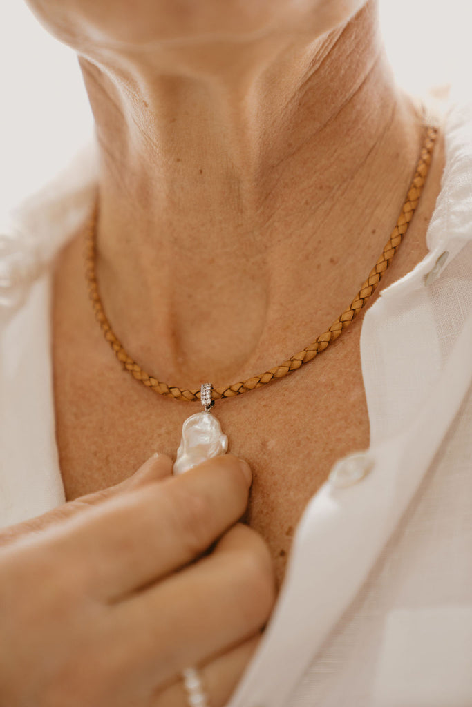 close up of a person wearing freshwater pearl and leather necklace
