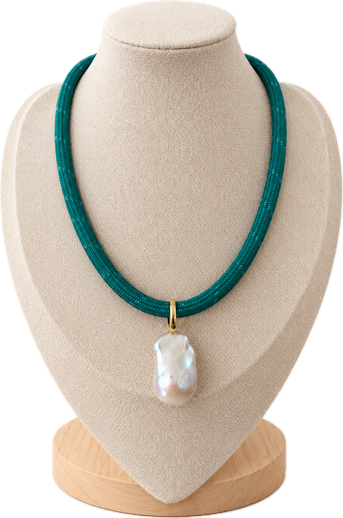 A teal beaded necklace with a baroque pearl pendant and gold clasp, displayed on a beige fabric jewelry bust.